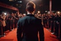 Handsome Man In Suit Stands Backwards On The Red Carpet In Front Of The Paparazzi. Generative AI