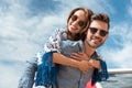 handsome man in sunglasses piggybacking his smiling girlfriend