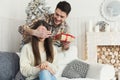 Handsome man surprising girl with Christmas present