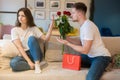 Handsome man surprising his beautiful wife with roses after being guilty, she shows his back off sign