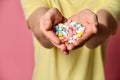 A handsome man in T-shirt on a pink background holding pills in his hand Royalty Free Stock Photo