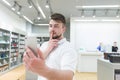 Handsome man takes a selfie on a smartphone in a tech store