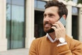 Handsome man talking on phone while walking outdoors, space for text Royalty Free Stock Photo