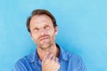 Handsome man thinking with hand to chin against blue wall Royalty Free Stock Photo