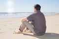 Handsome man thoughtful and sitting on the beach watching sea ocean dreaming Royalty Free Stock Photo
