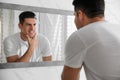 Handsome man touching his smooth face after shaving near mirror in bathroom Royalty Free Stock Photo