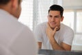 Handsome man touching his smooth face after shaving near mirror in bathroom Royalty Free Stock Photo