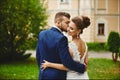 A handsome man in a trendy blue suit hugging and kissing a beautiful model woman in a wedding dress. A happy couple of Royalty Free Stock Photo