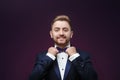 Handsome man in tuxedo and bow tie looking at camera. Fashionable, festive clothing. emcee on dark background Royalty Free Stock Photo