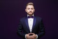 Handsome man in tuxedo and bow tie looking at camera. Fashionable, festive clothing. emcee on dark background Royalty Free Stock Photo