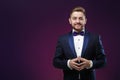 Handsome man in tuxedo and bow tie looking at camera. Fashionable, festive clothing. emcee on dark background Royalty Free Stock Photo