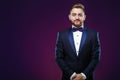 Handsome man in tuxedo and bow tie looking at camera. Fashionable, festive clothing. emcee on dark background Royalty Free Stock Photo