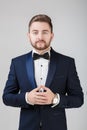 Handsome man in tuxedo and bow tie looking at camera. Fashionable, festive clothing. emcee on grey background Royalty Free Stock Photo