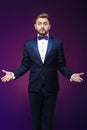 Handsome man in tuxedo and bow tie is surprised, throws his hands. compere in fashionable, festive clothing Royalty Free Stock Photo