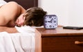 Handsome man using clock in bed after waking up in the morning. Lazy man happy waking up in the bed rising hands in the Royalty Free Stock Photo