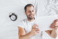 Handsome man using a digital tablet in bed Royalty Free Stock Photo