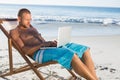 Handsome man using his laptop while relaxing on his deck chair Royalty Free Stock Photo