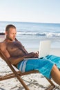 Handsome man using his laptop sitting on his deck chair Royalty Free Stock Photo