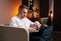 Handsome man using laptop while sitting in soft armchair Royalty Free Stock Photo
