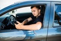 Handsome Young Man using mobile phone while driving a car Royalty Free Stock Photo