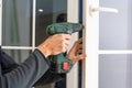 Handsome man using a screwdriver to install a window handle and looking at the camera. Making a house cozy and warm Royalty Free Stock Photo