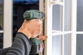 Handsome man using a screwdriver to install a window handle and looking at the camera. Making a house cozy and warm Royalty Free Stock Photo