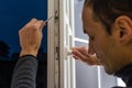 Handsome man using a screwdriver to install a window handle and looking at the camera. Making a house cozy and warm Royalty Free Stock Photo