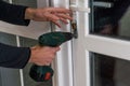 Handsome man using a screwdriver to install a window handle and looking at the camera. Making a house cozy and warm Royalty Free Stock Photo