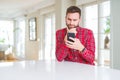 Handsome man using smartphone serious face thinking about question, very confused idea