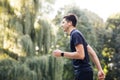 Handsome man using trendy earphones and smart watch. Sporty person training outside enjoying fresh nature. Healthy