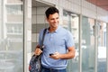 Handsome man walking with mobile phone and bag in city Royalty Free Stock Photo