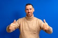 Handsome man wearing brown turtleneck giving thumbs up positive hand gesture smiling and happy for success. Winning Royalty Free Stock Photo