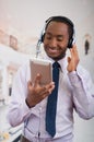 Handsome man wearing headphones with microphone, white striped shirt and tie, posing holding tablet in hand, smiling Royalty Free Stock Photo