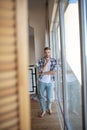 Handsome man wearing jeans standing in light spacious room