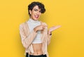 Handsome man wearing make up and woman clothes amazed and smiling to the camera while presenting with hand and pointing with Royalty Free Stock Photo