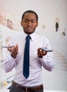 Handsome man wearing shirt and tie holding up two mobile phones with stressed facial expression Royalty Free Stock Photo