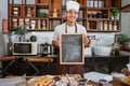 Handsome man wearing a smiling apron holding a blackboard