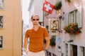 Handsome man wearing sunglasses and shirt walking in old town street Royalty Free Stock Photo