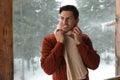 Handsome man wearing warm sweater and scarf on snowy day. Winter season