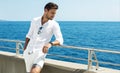 Handsome man wearing white clothes posing in sea scenery