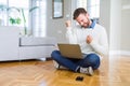Handsome man wearing working using computer laptop very happy and excited doing winner gesture with arms raised, smiling and Royalty Free Stock Photo