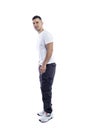 A handsome man in a white T-shirt and blue casual trousers stands tall. Muscular brunette guy with a beard. Isolated on a white Royalty Free Stock Photo