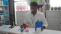 Handsome man working in a pharmacy holding a barcode scanner and using a tablet with various pharmaceutical products displayed on Royalty Free Stock Photo