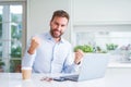 Handsome man working using computer laptop and drinking a cup of coffee screaming proud and celebrating victory and success very Royalty Free Stock Photo