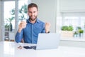 Handsome man working using computer laptop and drinking a cup of coffee screaming proud and celebrating victory and success very Royalty Free Stock Photo