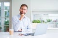 Handsome man working using computer laptop and drinking a cup of coffee serious face thinking about question, very confused idea Royalty Free Stock Photo