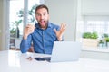 Handsome man working using computer laptop and drinking a cup of coffee very happy and excited, winner expression celebrating Royalty Free Stock Photo