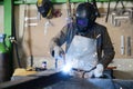 Handsome man workshop welding iron spark fire hot steel with a power GMAW welder and protective gear Royalty Free Stock Photo