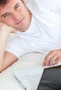 Handsome man writing on his laptop in his bedroom