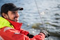 Handsome man on yacht touches white sail called assymetric spinnaker, works with tackle in sea at summer day, under view